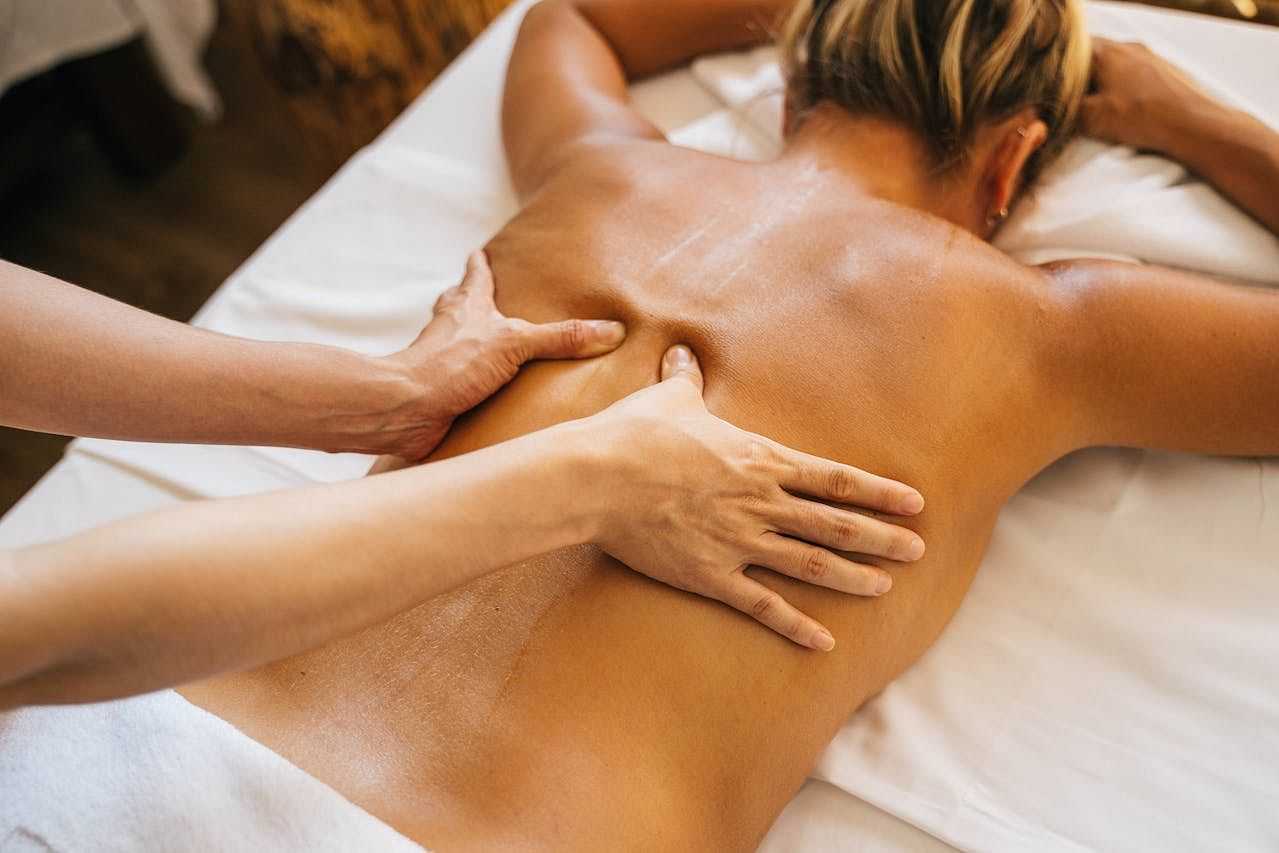 Person receiving a relaxing back massage on a white massage table.