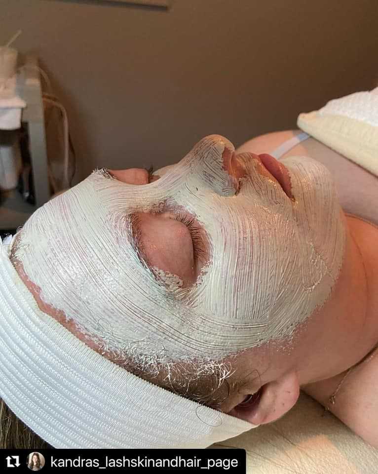 Person receiving a facial treatment with a white mask applied on their face in a spa setting.